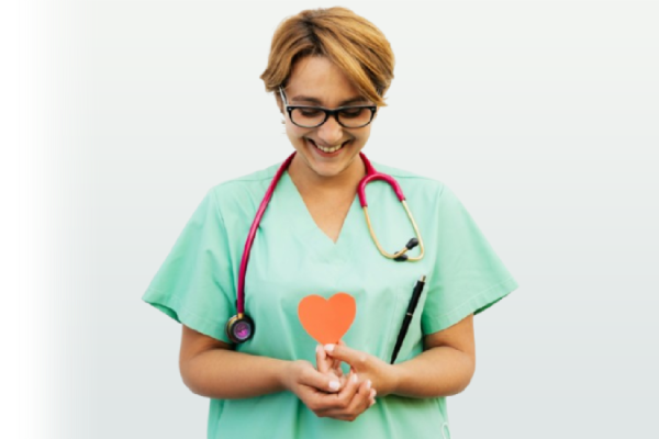 Smiling female healthcare professional in green scrubs holding a heart cut-out, symbolizing compassionate and heartfelt care by the team of TrustScape Medical Services