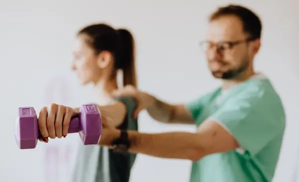 Physiotherapist assisting an elderly patient with shoulder rehabilitation and therapeutic exercises.